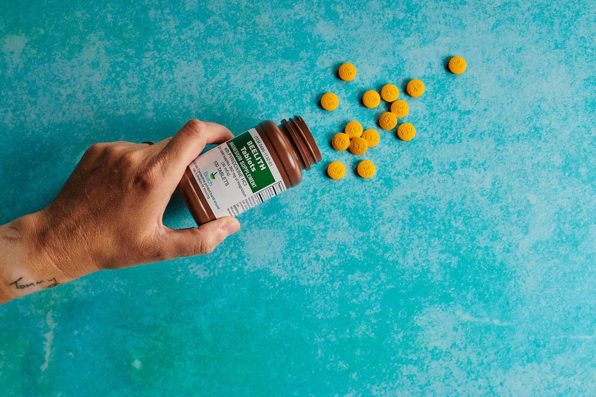 Woman taking probiotics capsules with glass of water at breakfast table showing how to take probiotics capsules correctly